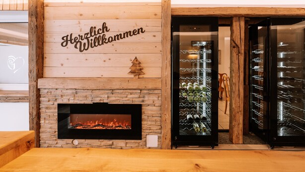 Un mur en bois avec une cheminée et une pancarte sur laquelle on peut lire : « Herzlich Willkommen ».