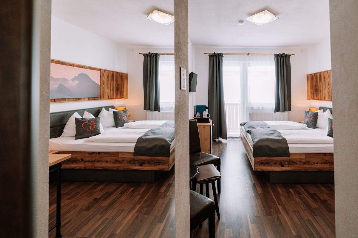 Une chambre d’hôtel avec deux lits, des têtes de lit en bois, un bureau et une vue sur les montagnes par la fenêtre.
