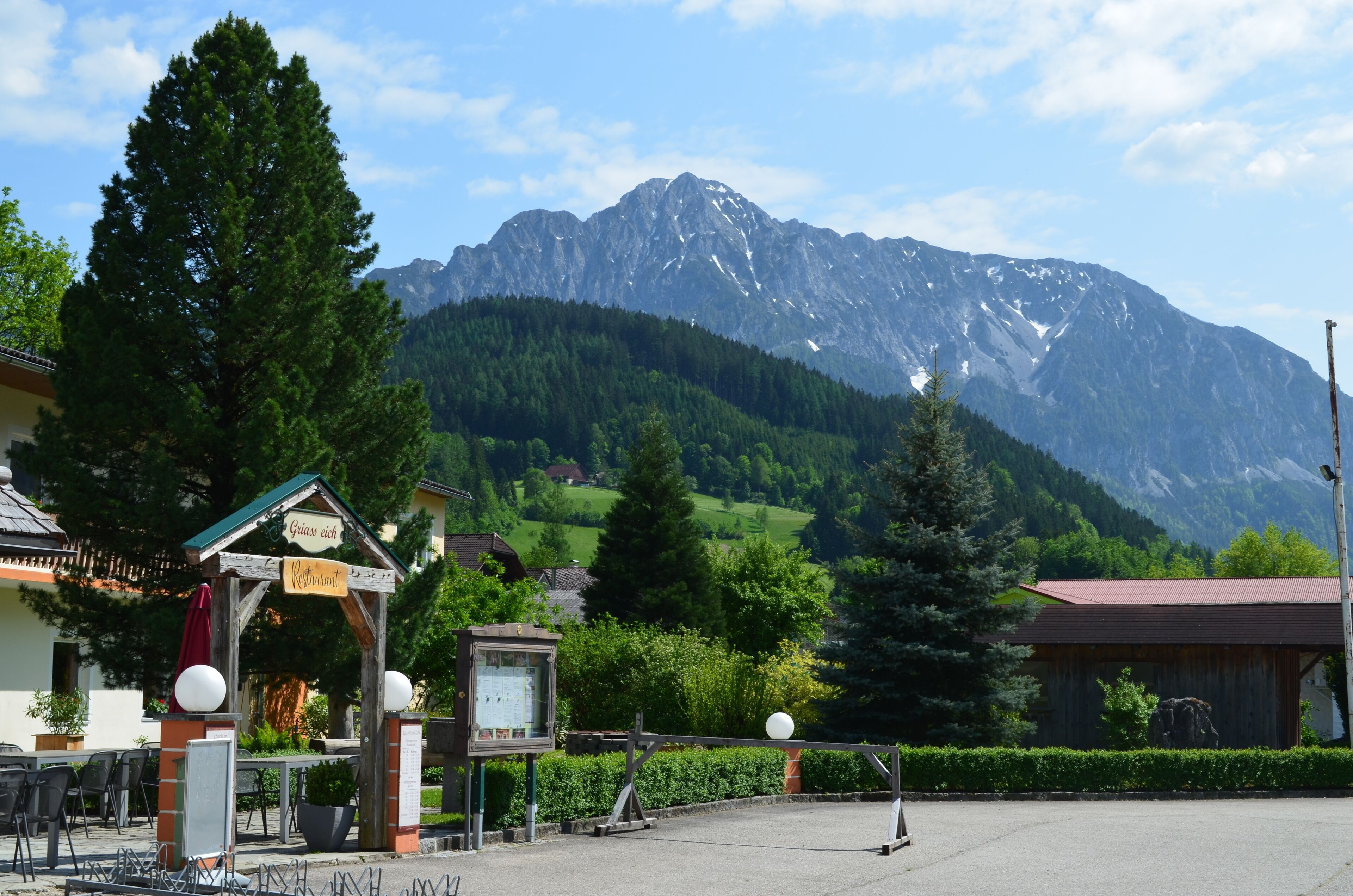 A mountain-view restaurant with outdoor seating and a wooden structure with a sign.