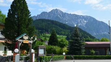 A mountain-view restaurant with outdoor seating and a wooden structure with a sign.