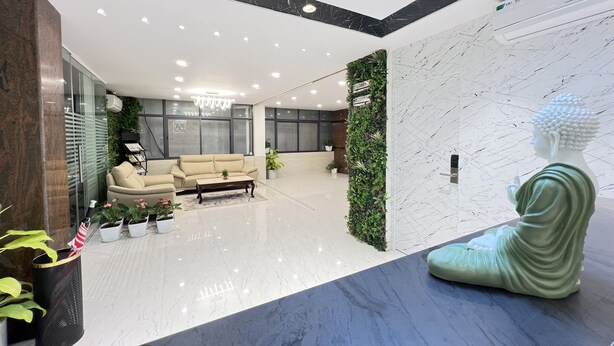 A modern lobby with a marble reception desk, a beige sofa, and a Buddha statue. - The Auberge - Boutique Hotel (Bengaluru)