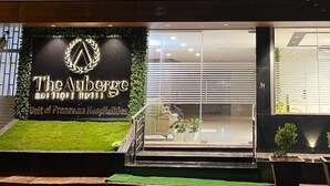 The Auberge Boutique Hotel with a well-lit entrance, a grassy area, and potted plants. - The Auberge - Boutique Hotel (Bengaluru)