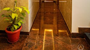 A hotel lobby with a marble floor, a potted plant, and a wooden door at the end. - The Auberge - Boutique Hotel (Bengaluru)