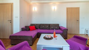 A modern living room with a sectional sofa, purple cushions, a white coffee table, and a glass of orange juice. - Anto - 3 bedroom apartment in Trogir (Trogir)