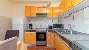 A compact kitchen with orange cabinets, a stove, a microwave, and a sink. - Anto - 3 bedroom apartment in Trogir (Trogir)