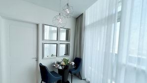 A modern dining area with a round table, two chairs, and a decorative light fixture. -  Cozy 1b With Balcony in Business Bay (Dubai)