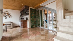 A spacious living area with a wooden ceiling, a kitchen area, and a staircase leading to an upper floor. - My Georgian village (Sagarejo)