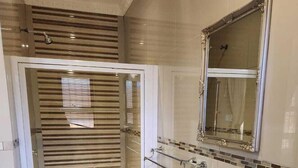 A bathroom with a shower, a sink, and a mirror. - Suits bar restaurant and guesthouse (Merafong City)