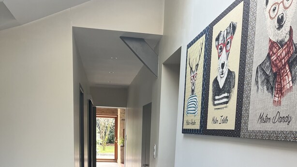 Un pasillo con un banco de madera, plantas en macetas y obras de arte en la pared.