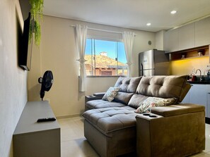 A modern living room with a sofa, a TV, and a fan.