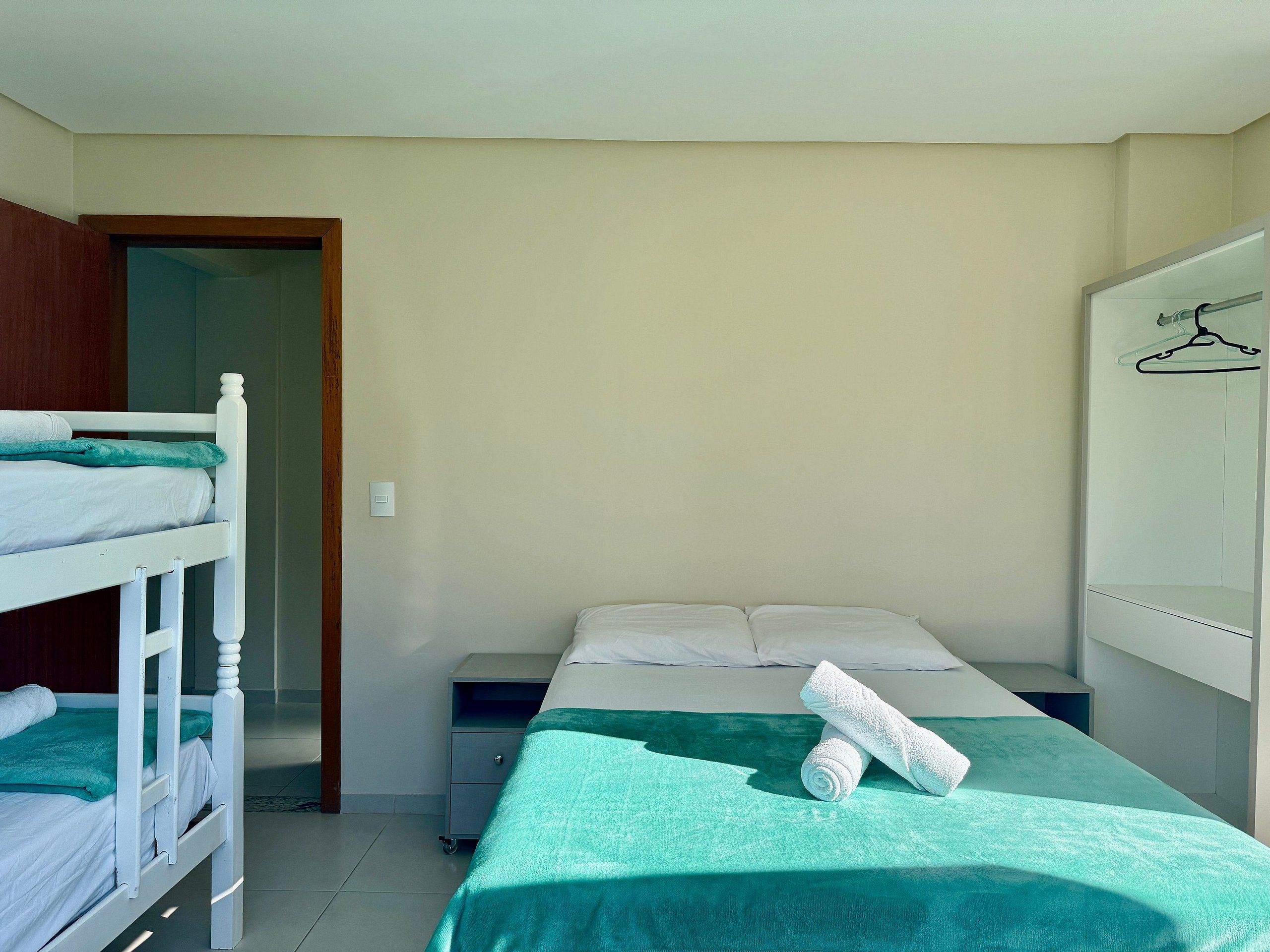 A bedroom with bunk beds, a single bed, a green bedspread, and a whiteboard with a hanger drawing.
