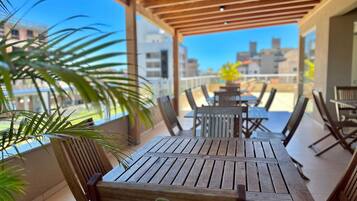 A wooden deck with tables and chairs, overlooking a cityscape.
