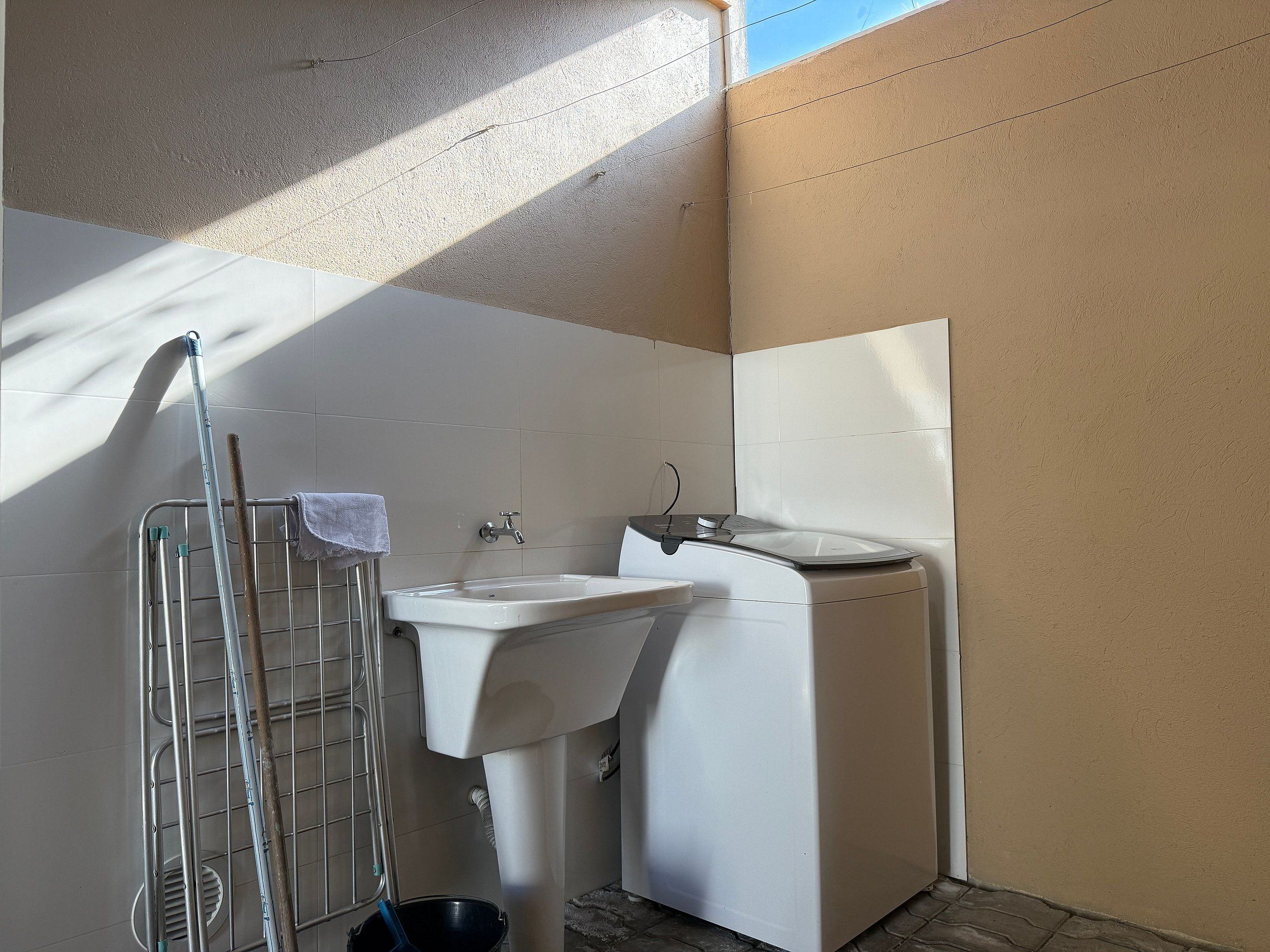 Un baño pequeño y limpio con lavamanos, espejo y zona de ducha.