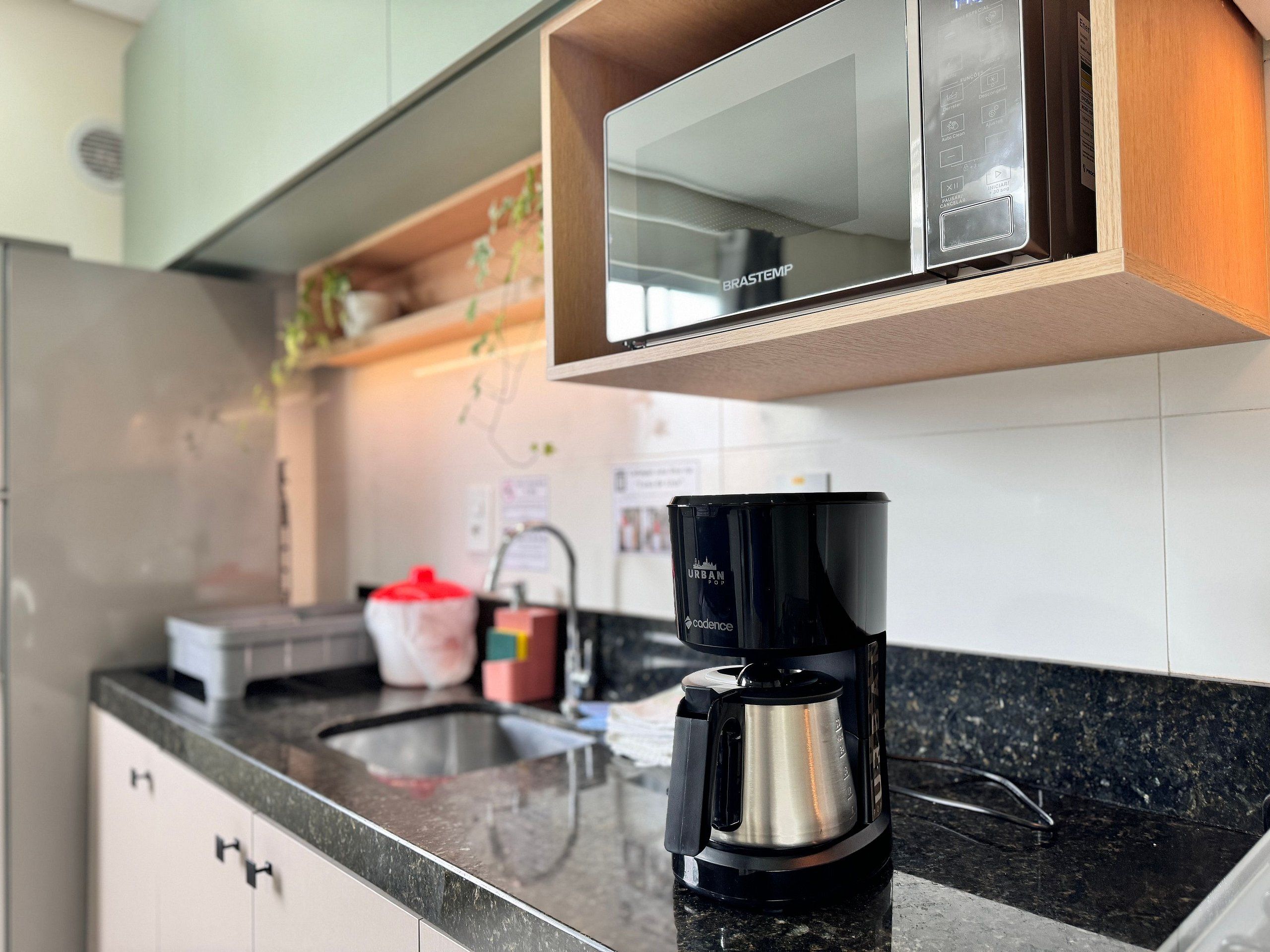 A kitchen with a coffee maker on the counter, a microwave above, and a sink with a faucet.