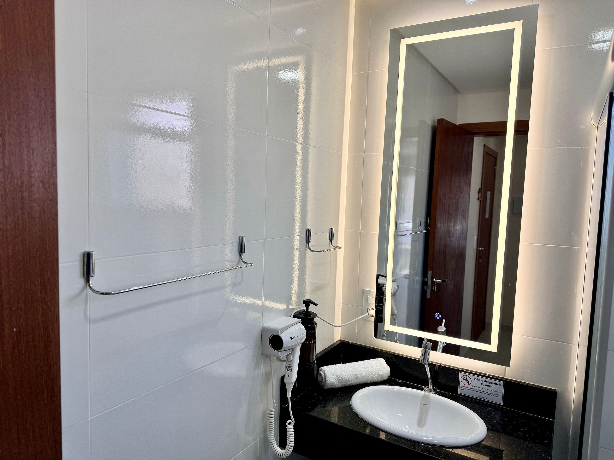 Un baño moderno con lavamanos blanco, un espejo y un secador de pelo.