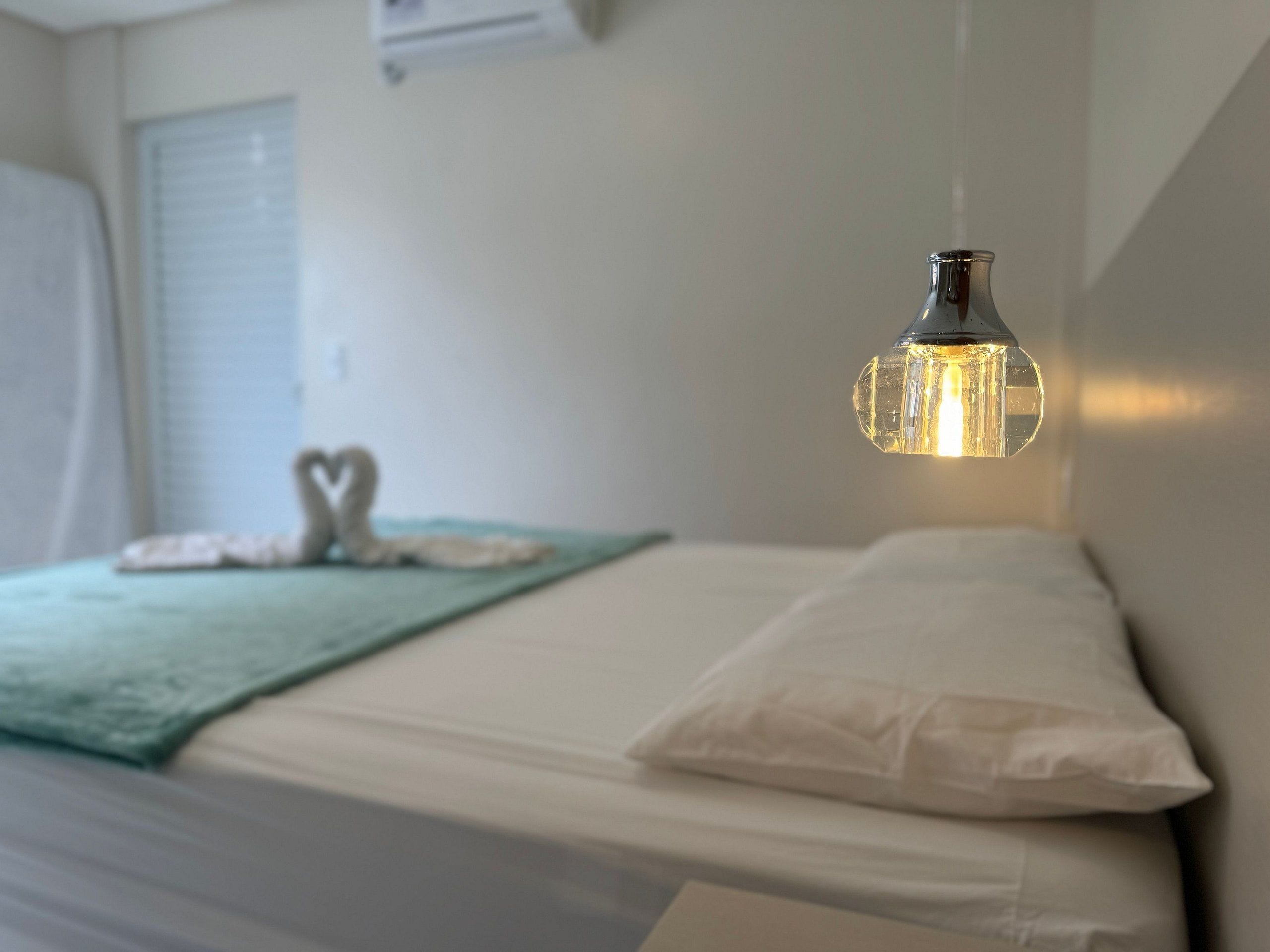 Een bed met witte beddengoed en een hartvormige decoratie op het kussen.