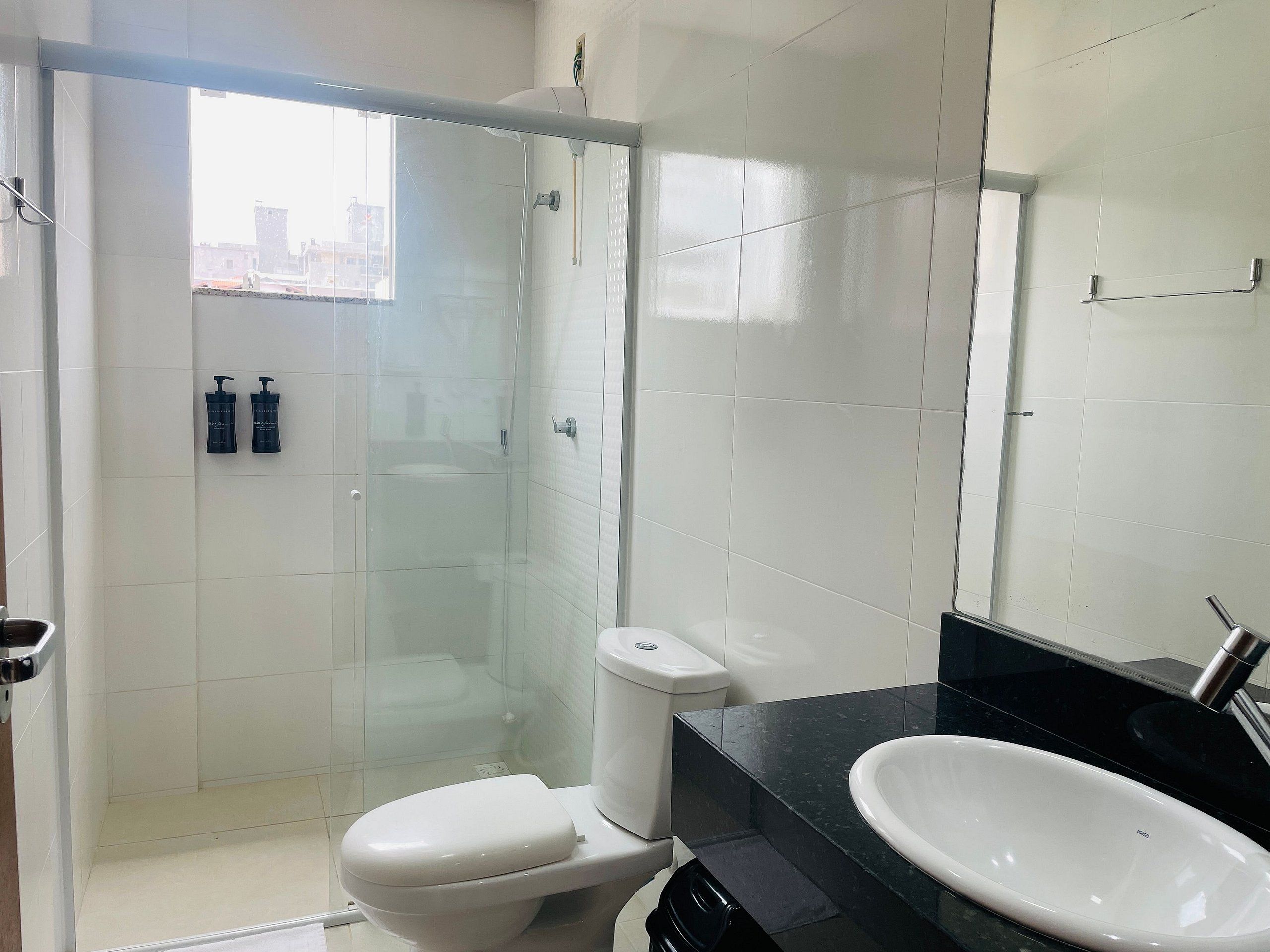 A modern bathroom with a glass-enclosed shower, a white toilet, and a black countertop with a white sink.
