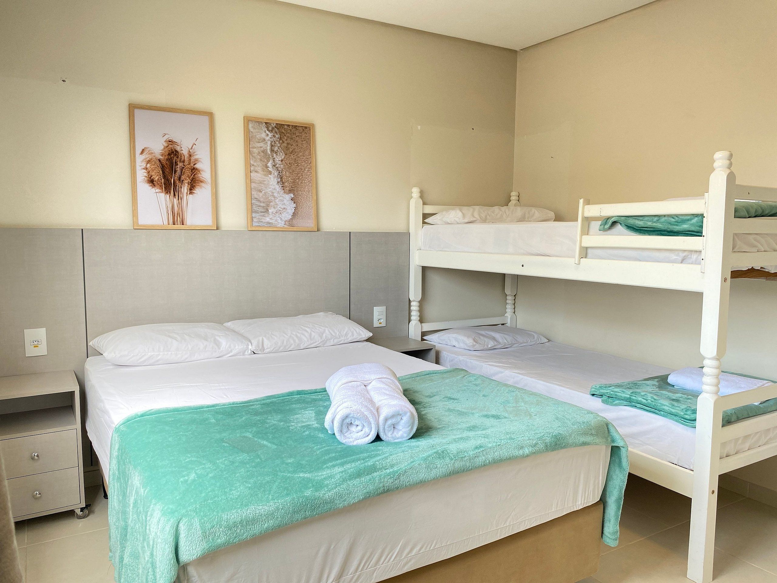 Une chambre avec un lit superposé, une table de chevet et deux tableaux encadrés accrochés au mur.