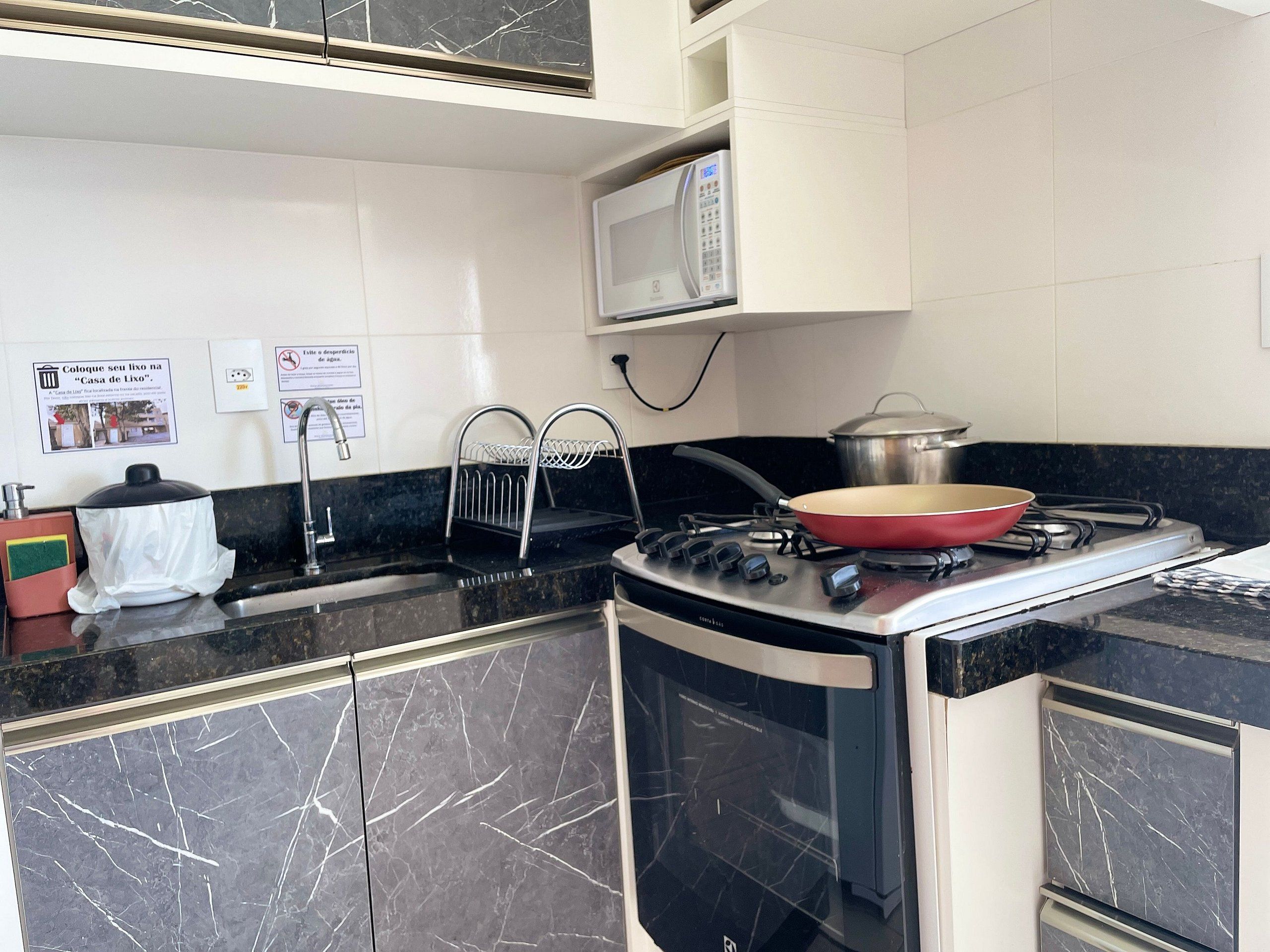 A compact kitchen with a stove, microwave, and sink.