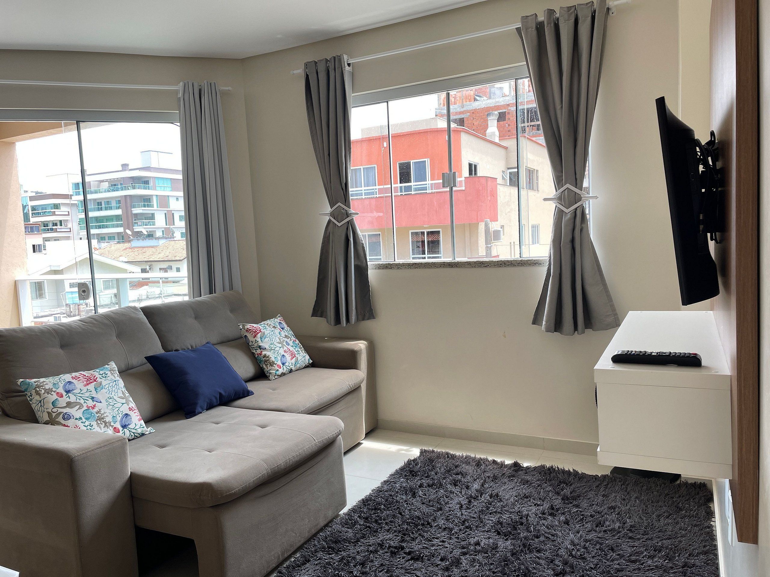 A living room with a sofa, a rug, and a TV on a stand.