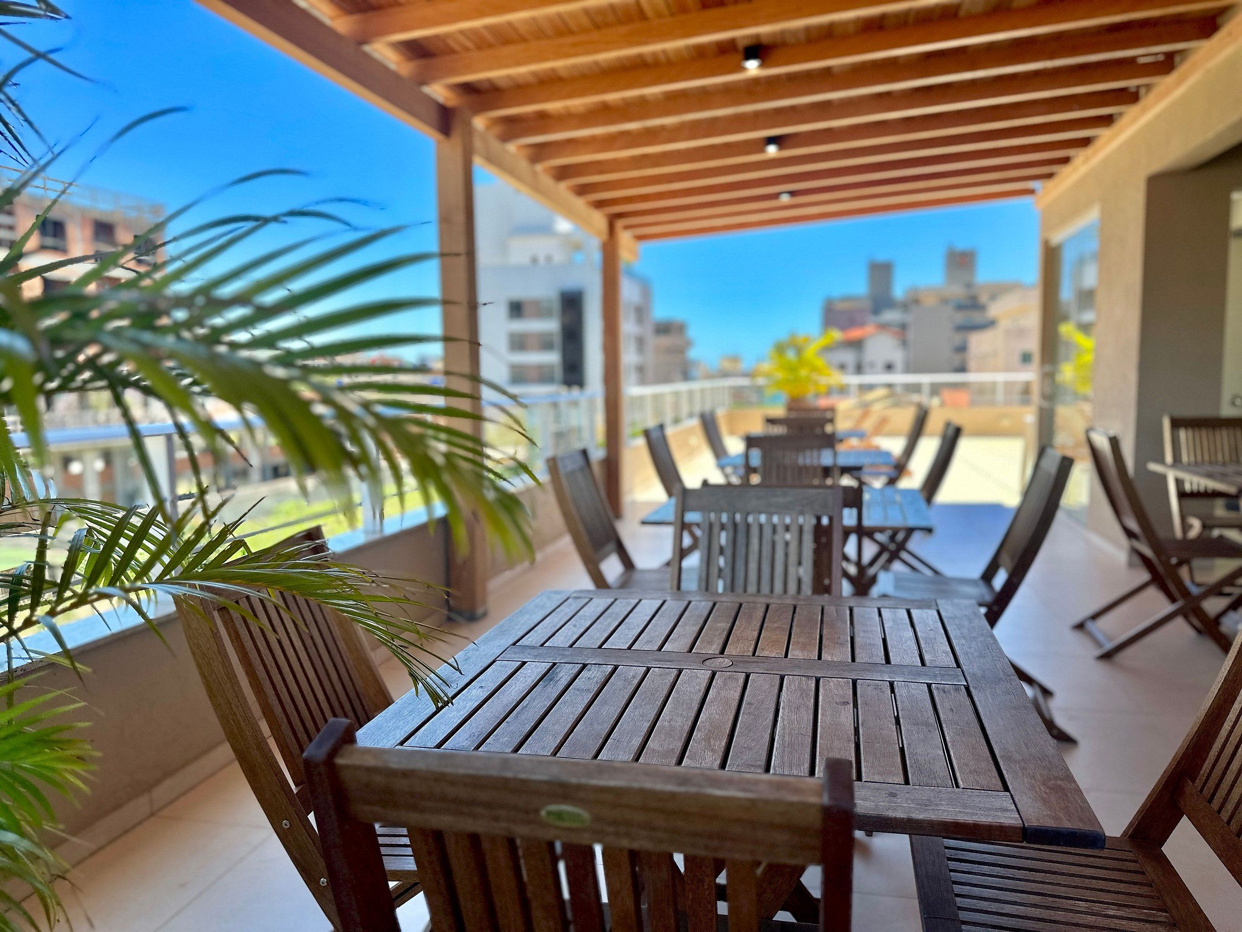 A wooden deck with tables and chairs, overlooking a cityscape.