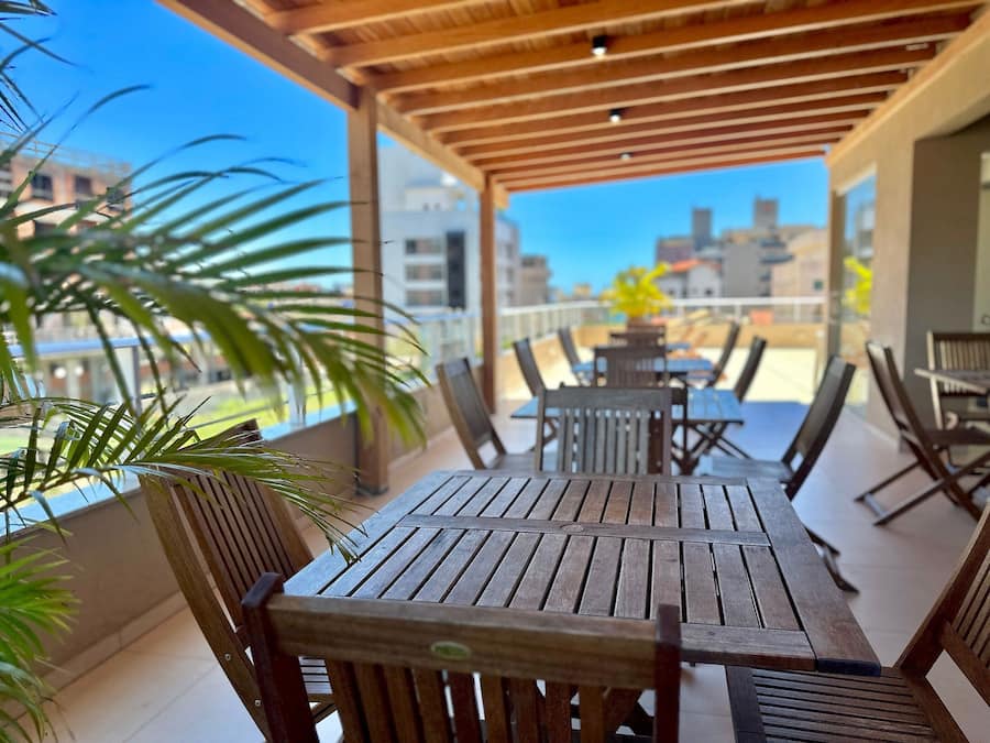 A wooden deck with tables and chairs, overlooking a cityscape.