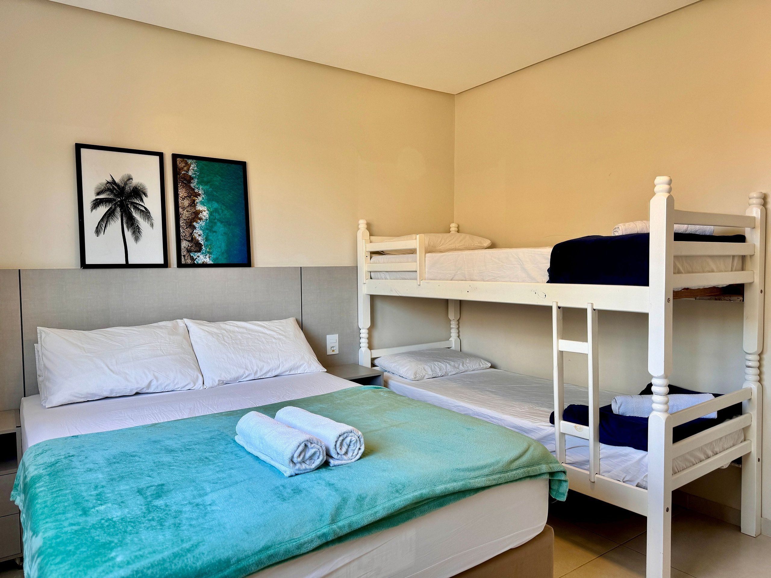 A bunk bed room with a bed, two framed pictures on the wall, and a green blanket on the bed.