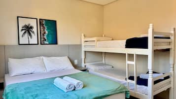 A bunk bed room with a bed, two framed pictures on the wall, and a green blanket on the bed.