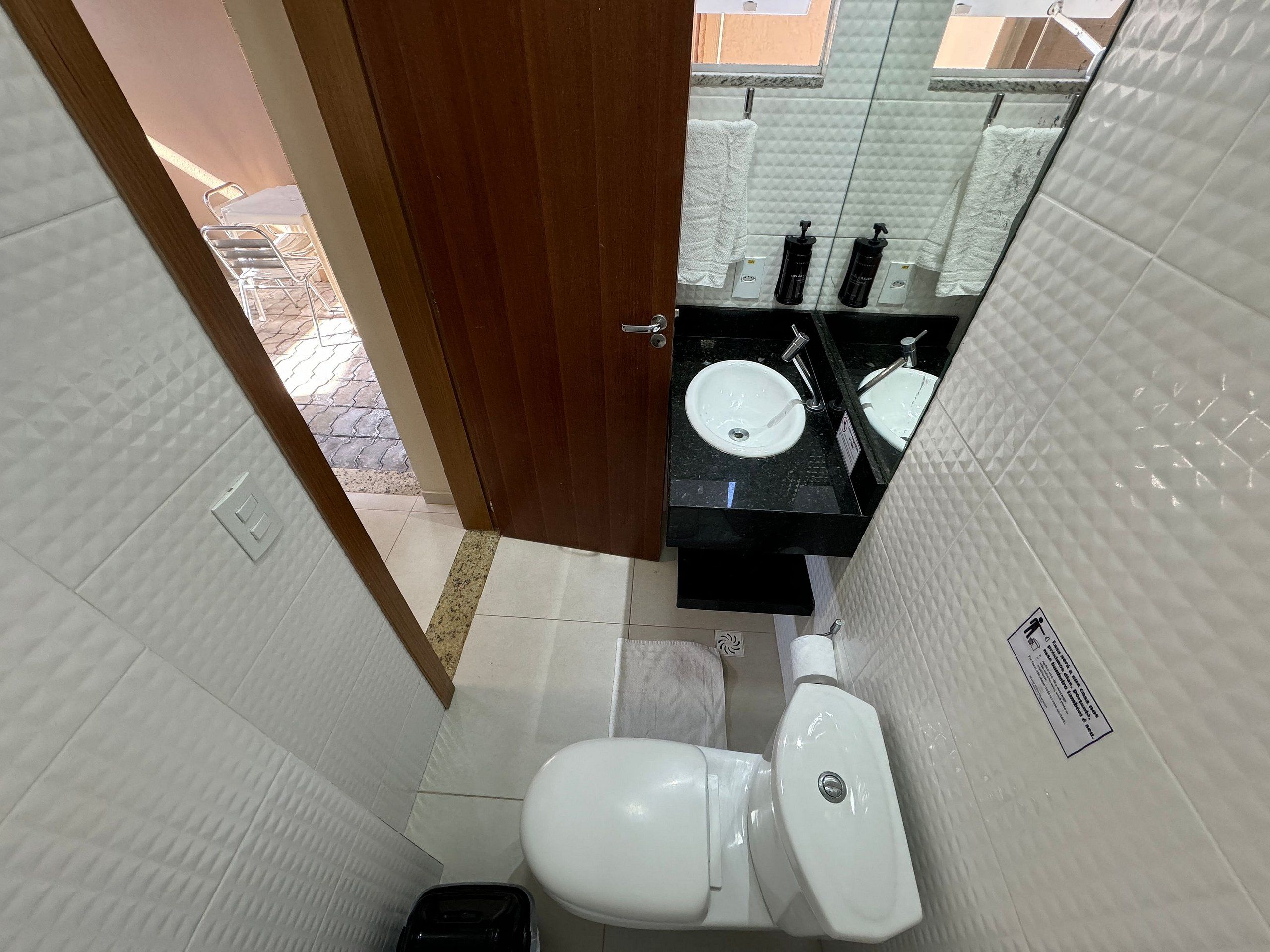 A compact bathroom with a white toilet, a sink with a black countertop, and a mirror above the sink.