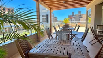 A wooden deck with tables and chairs, overlooking a cityscape.