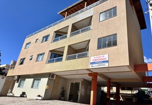 A multi-story building with a sign indicating it is a temporary lodging. - Maria Julia (Bombinhas)