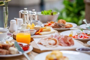 Enjoy a delicious breakfast spread with a variety of cheeses, meats, fresh fruits, condiments, and a salad.