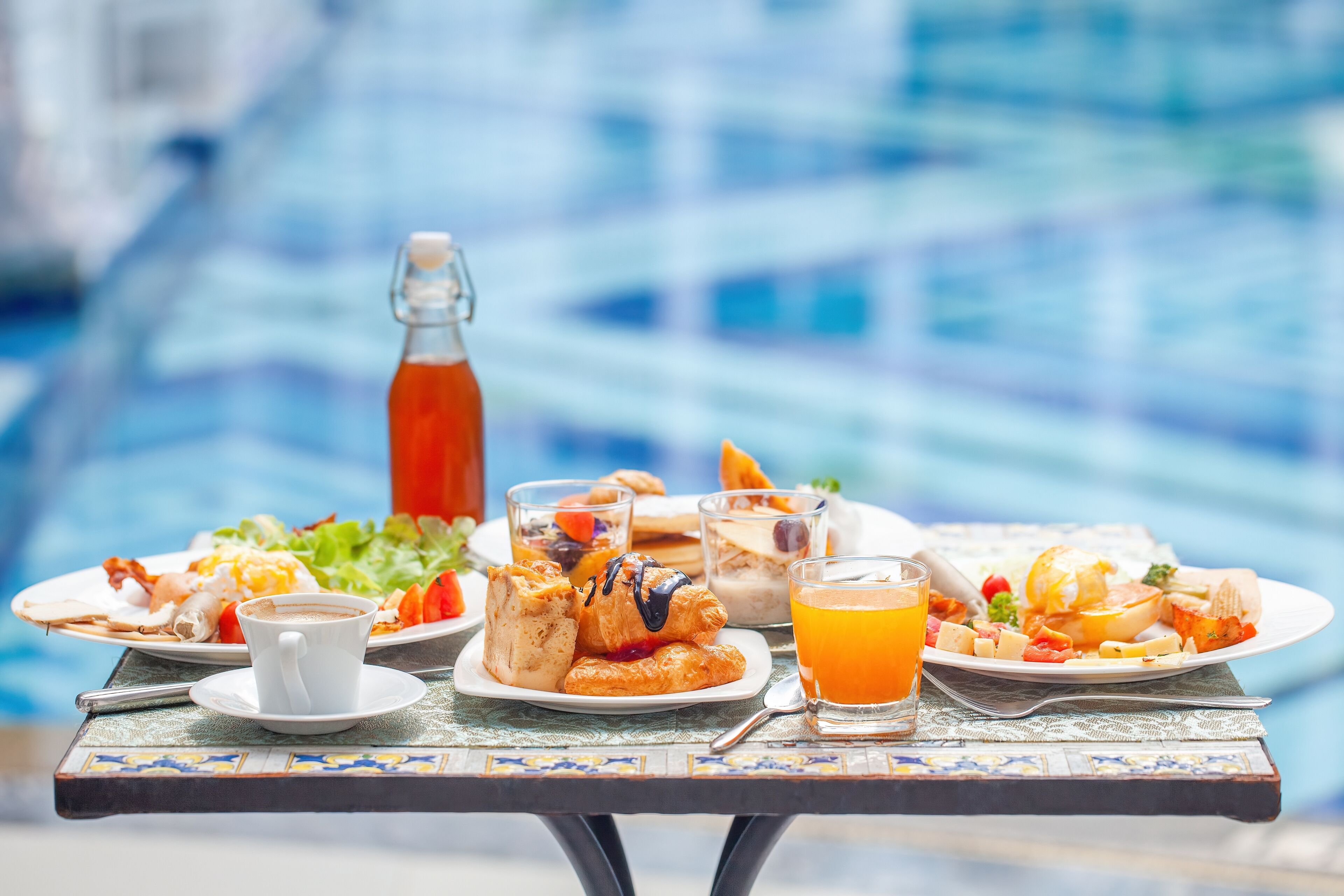 Una mesa de comedor con alimentos para el desayuno, incluyendo bollos, un vaso de zumo de naranja y una botella de jugo.