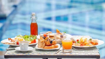 Una mesa de comedor con alimentos para el desayuno, incluyendo bollos, un vaso de zumo de naranja y una botella de jugo.