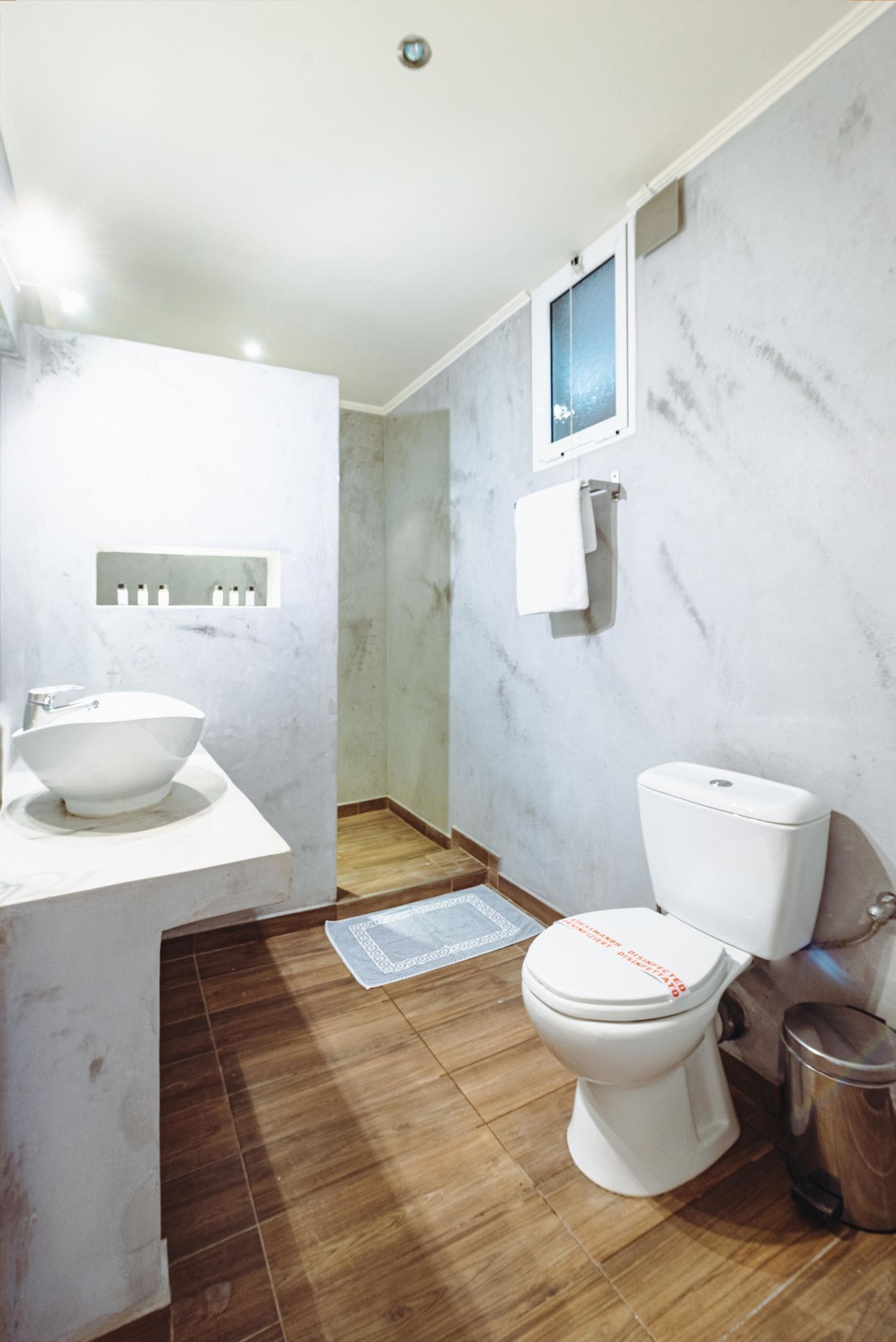 Uma casa de banho moderna com parede de mármore, lavatório branco e sanita.