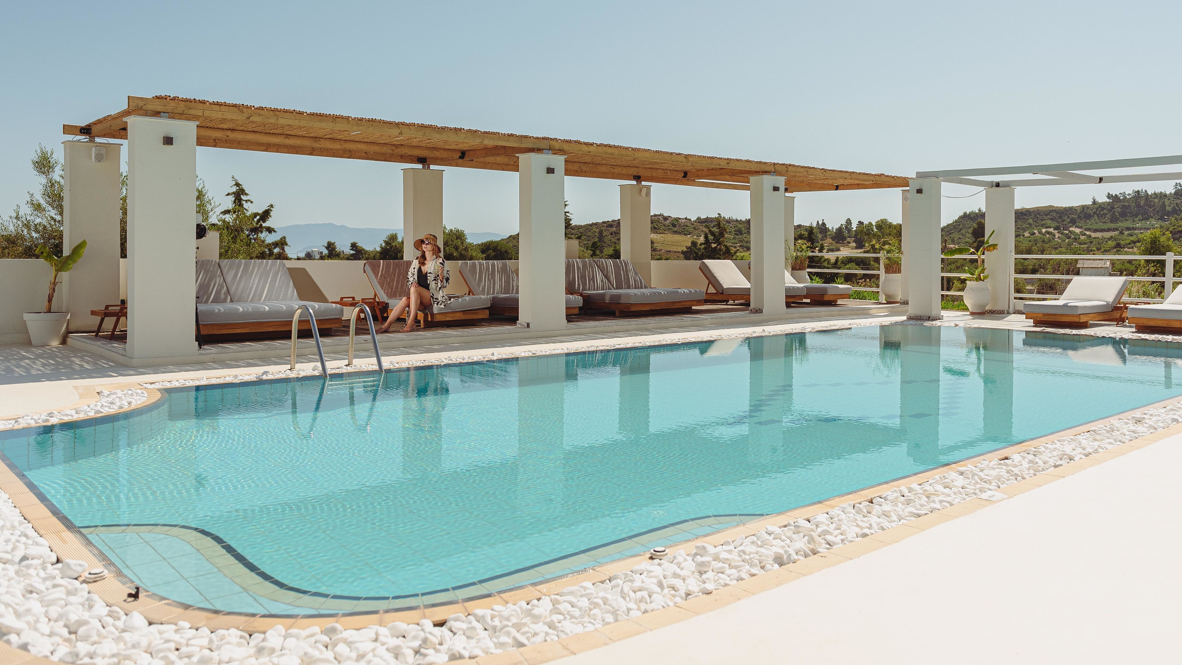 Une piscine avec des chaises longues et une pergola.