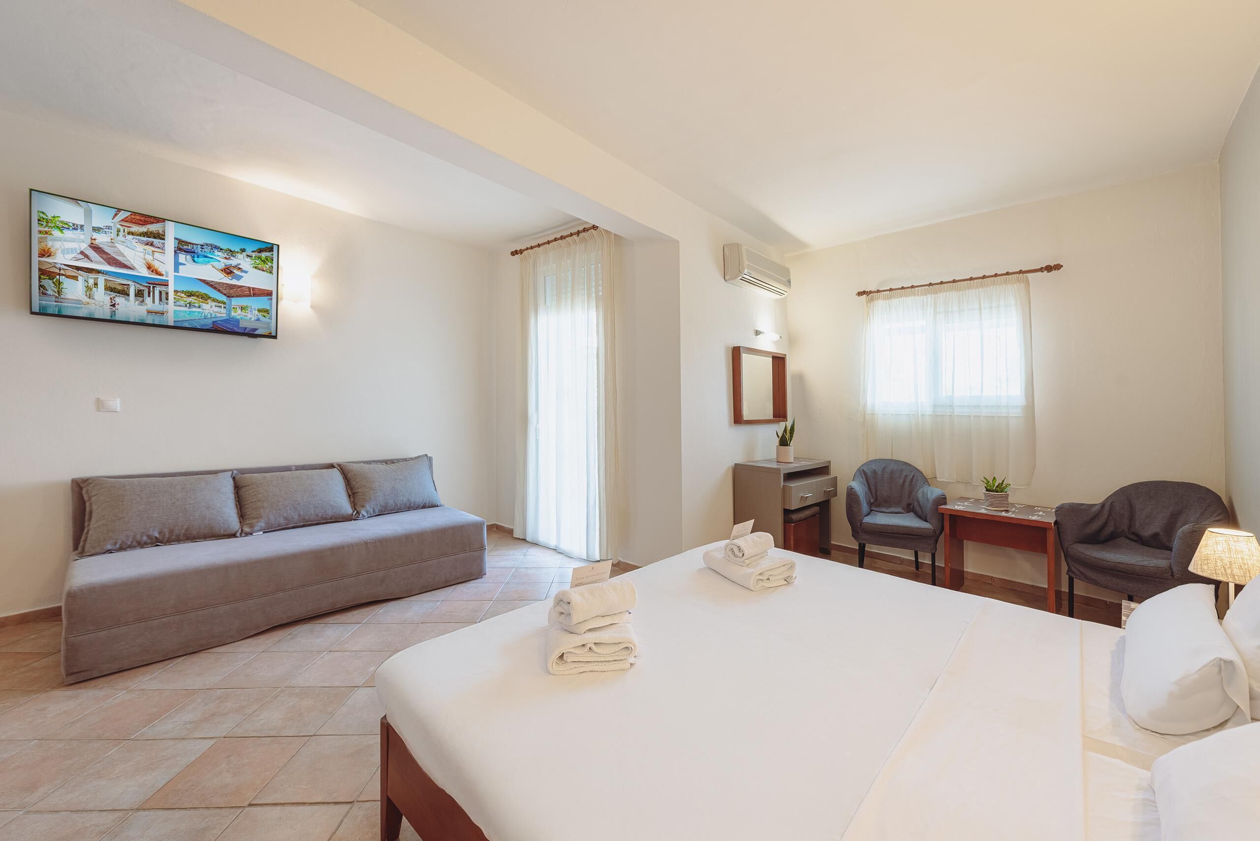A hotel room with a bed, a sofa, a desk, and a chair.