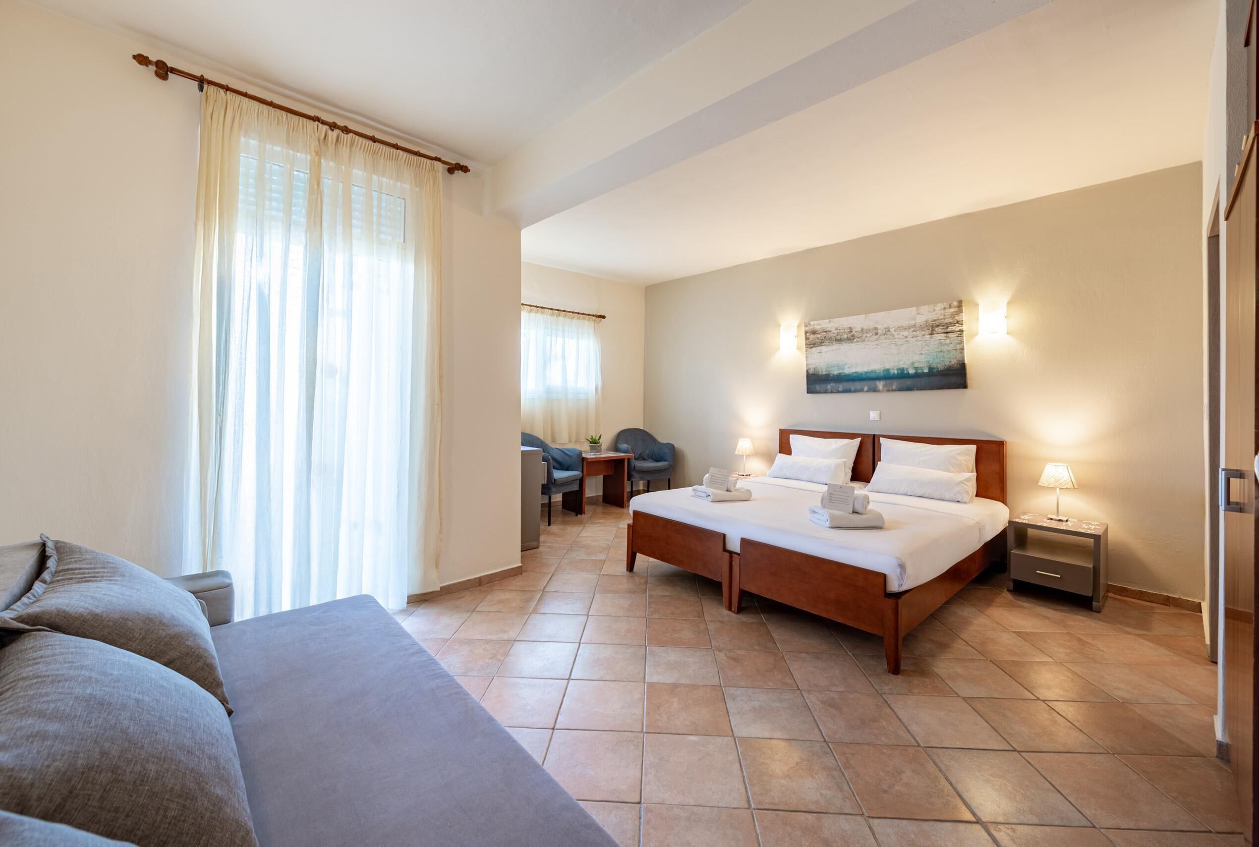 A hotel room with a bed, a sofa, a desk, and a chair.
