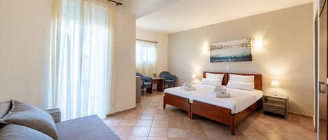A hotel room with a bed, a sofa, a desk, and a chair.