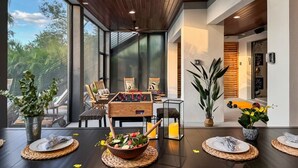 Ein modernes Interieur mit Fußballtisch, Essbereich und großen Fenstern.