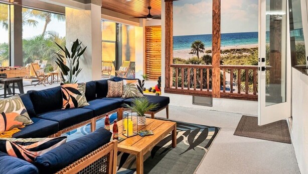 Ein geräumiger Wohnbereich mit einer Couch, einem Couchtisch und Blick auf den Strand durch eine Glastür.