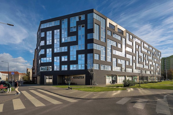 A modern multi-story building with a prominent 'STARTER' sign, a pedestrian crossing, and a clear sky.