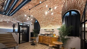A modern interior with exposed brick walls, a kitchen area, wooden flooring, and a staircase. - CC Opera Suites (Madrid)