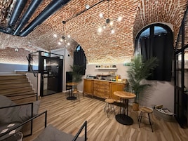 A modern interior with exposed brick walls, a kitchen area, wooden flooring, and a staircase.
