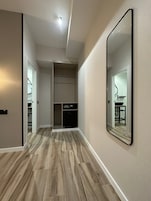 A hallway with a wooden floor, a built-in wardrobe, and a large mirror on the wall.