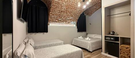 Una habitación con techo de ladrillo, dos camas, un armario y un espejo.