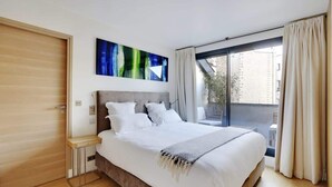 A modern bedroom with a large bed, a wooden wardrobe, and a cityscape view through a large window. - A Stunning 2-BR/2BA with Terraces and A/C (Paris)
