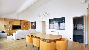 A modern living room with a wooden dining table and yellow chairs, a white sofa, and a TV on a wooden shelf. - A Stunning 2-BR/2BA with Terraces and A/C (Paris)