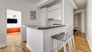 A modern kitchen with white cabinets, a wooden countertop, and a dining area with a table and chairs. - A Nice 1-BR in Saint-Germain (Paris)