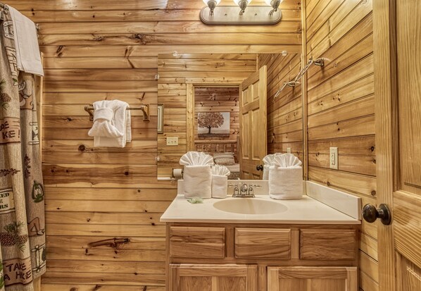 Een houten badkamer in een chalet, met een wastafel, spiegel en handdoeken.